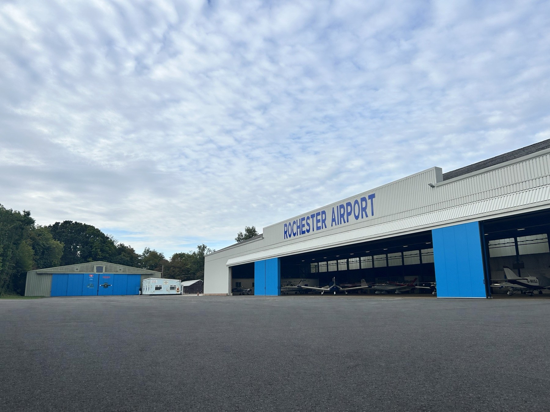 The main hangar at Rochester Airport with its doors open and aircraft inside
