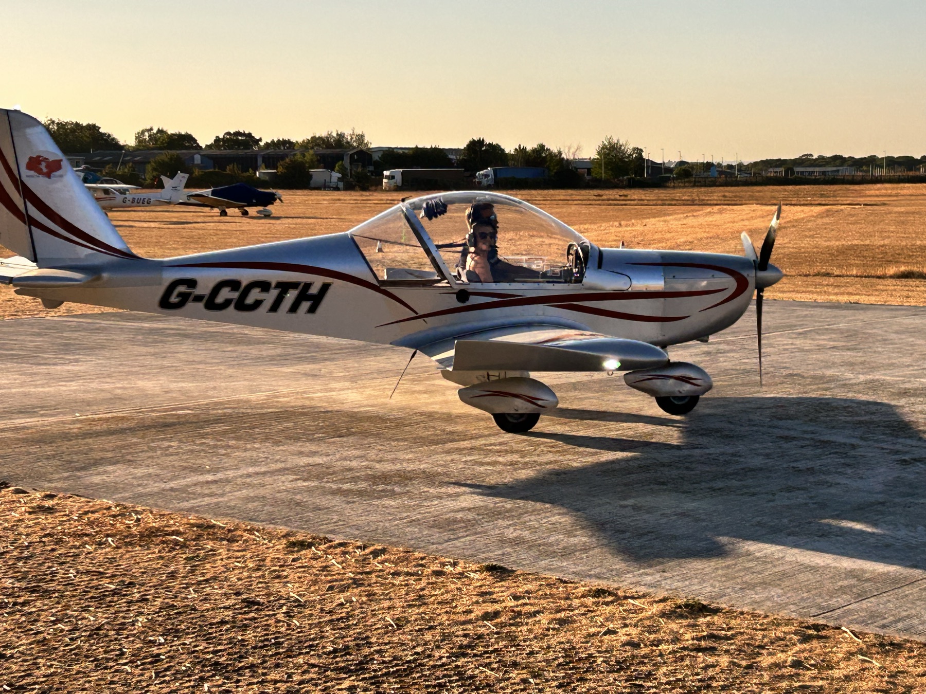 A microlight taxiing on the apron at Rochester Airport at sunset